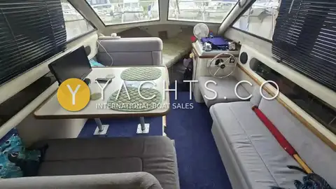 Carver 26 Command Bridge: saloon with grey dinette, table, blue carpet and lower helm seat forward