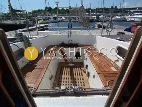 Contessa 32: cockpit from companionway with teak seats, teak grating and wooden tiller, marina behind