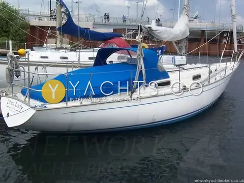 Contessa 32: port quarter view of white hull with blue sprayhood and covers moored in marina