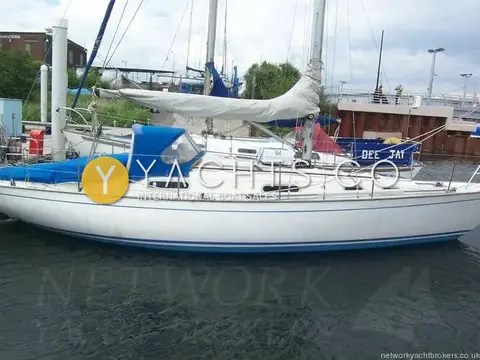 Contessa 32: starboard side profile of white hull with blue boot stripe, boom cover fitted