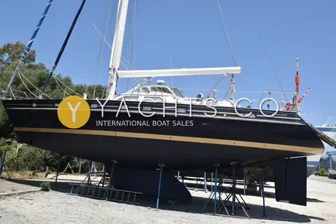 Contest 48CS: dark blue hull with gold cove stripes ashore on stands, showing wing keel and skeg-hung rudder