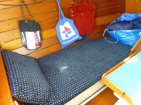 Cornish Crabber 22 Gaff Cutter: port bench seat with patterned cushion against wood-lined hull, bags hung above