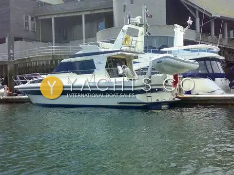 Cougar Advance 41 Boat For Sale: stern quarter showing tender on davits, bathing ladder and flybridge, berthed in a marina