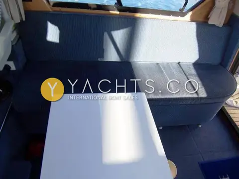 Cougar Advance 41 Boat For Sale: saloon with blue striped settee and white table, sunlight through the windows