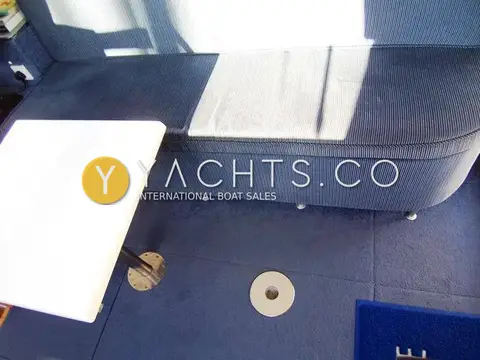 Cougar Advance 41 Boat For Sale: close view of saloon settee, white table on pedestal and blue carpeted sole