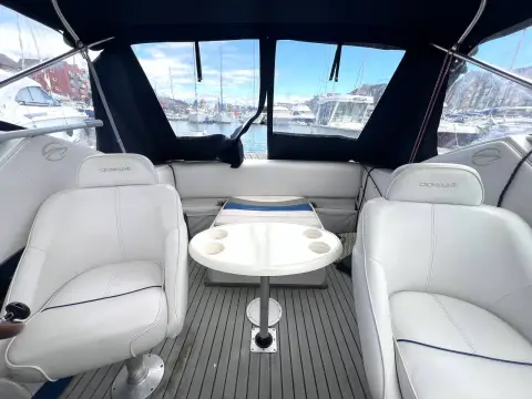 Crownline 210 CCR: cockpit under canopy with two white pedestal seats around a central pedestal table