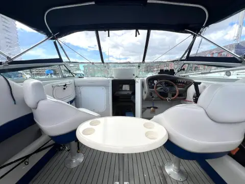 Crownline 210 CCR: cockpit looking forward to helm, with white seats, round table and grey decking
