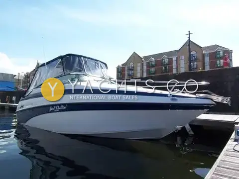 Crownline 230 CCR: starboard bow view of the blue and white hull with canopy up at a marina pontoon