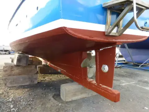 Custom Built John Gaff 8.25 Fishing Boat: underwater hull ashore showing red antifouling, keel, rudder and propeller on blocks
