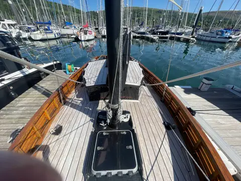 Unique Gaff Yawl: teak foredeck viewed from the mast, varnished bulwarks and marina beyond