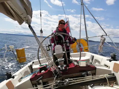 Dehler 38 CWS: helmsman at the wheel under sail in a breeze, lines led aft to the cockpit