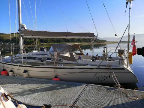 Dehler 38 CWS: port quarter alongside a pontoon in evening sun, spray hood and stern name visible