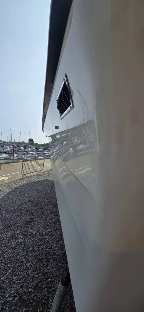 Draco 30: hull side out of the water on gravel hardstanding, showing glossy topsides and vent