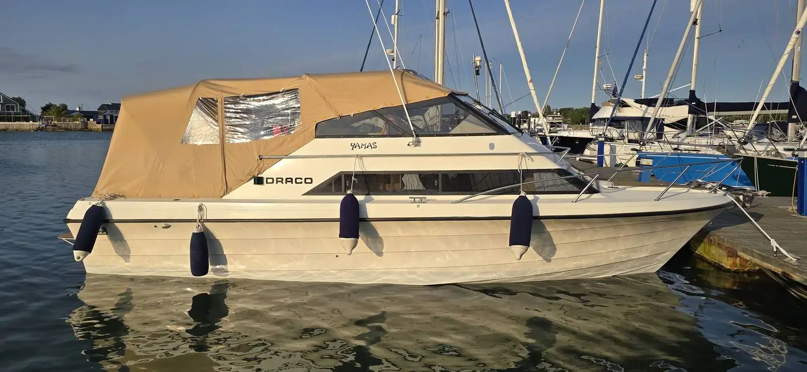 Draco 30: white hull afloat at a marina berth with beige canopy and fenders out