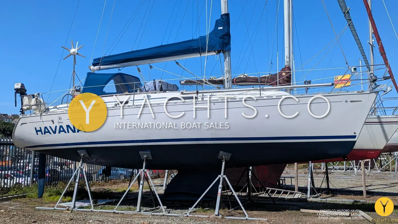 Dufour 36 Classic Owners Version: hull ashore on stands with blue boot stripe, wind generator and sprayhood fitted