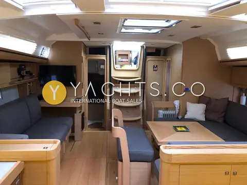 Dufour 520 Grand Large: saloon looking aft to companionway, grey sofas, TV above chart table and square folding table