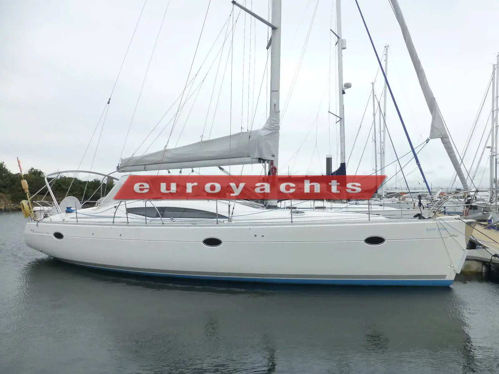 Elan Marine Impression 434: white hull with dark grey deck saloon windows, moored alongside a pontoon on an overcast day