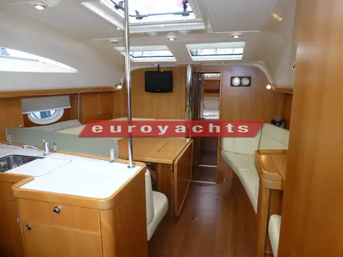 Elan Marine Impression 434: saloon with cream upholstery, wood joinery, galley counter in foreground and roof hatches overhead
