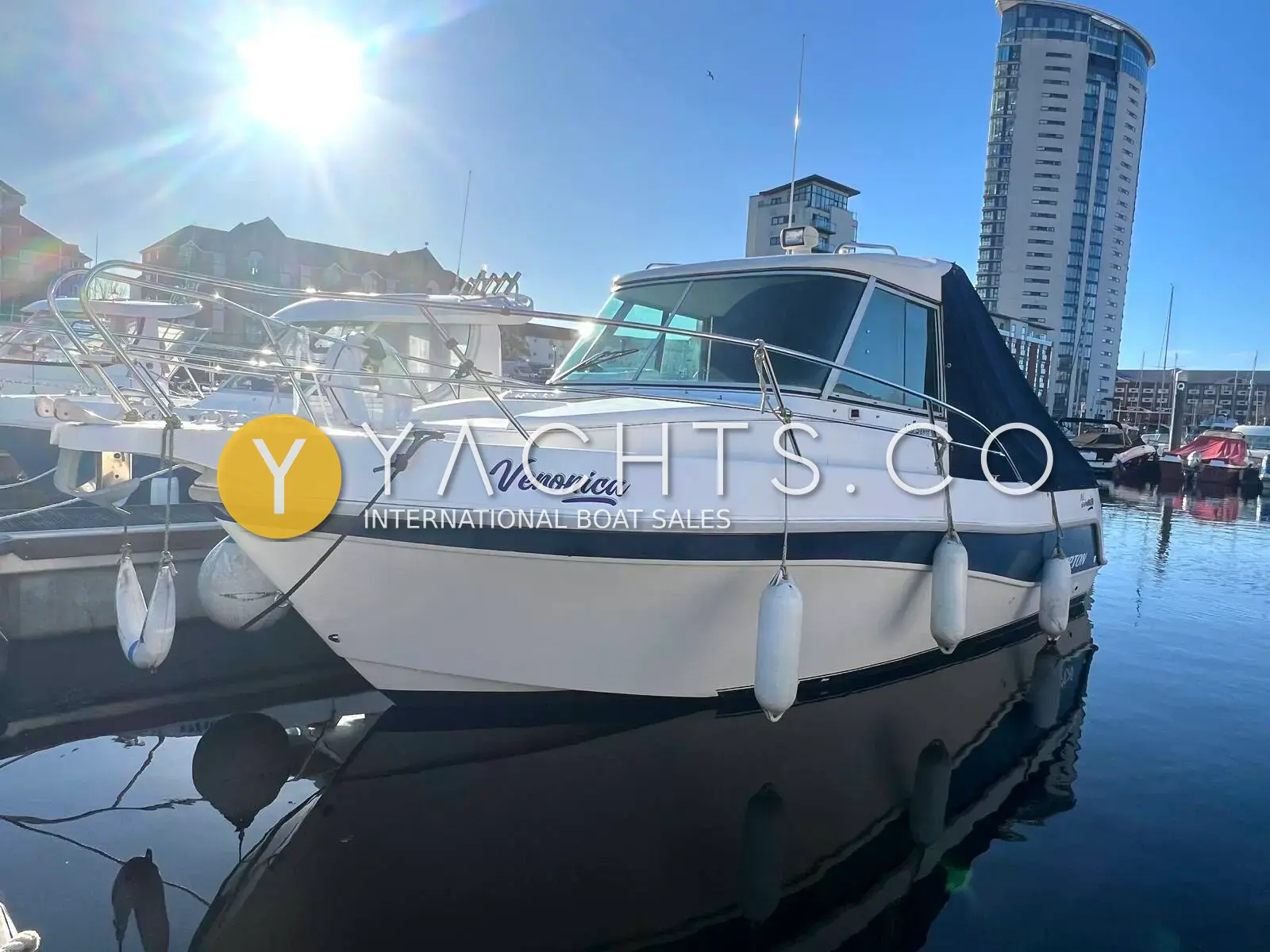 Faeton 630 Sport: white hull with dark wheelhouse hardtop, moored in a marina beside a tall tower block