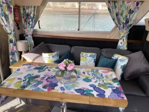 Fairline 40: saloon dining table with floral cloth before the settee, matching floral curtains at windows