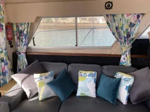 Fairline 40: grey saloon settee beneath large opening windows framed by floral curtains