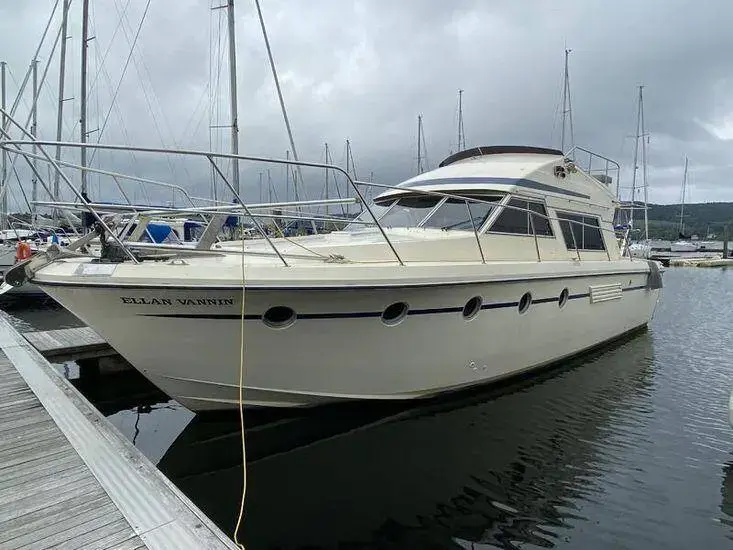 Fairline 40: white flybridge motor yacht moored alongside a pontoon in a marina under cloudy skies