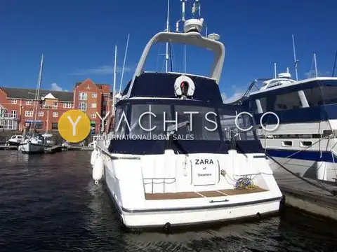 Fairline Phantom 41: stern view with navy cockpit canopy, teak bathing platform and name board in Swansea marina
