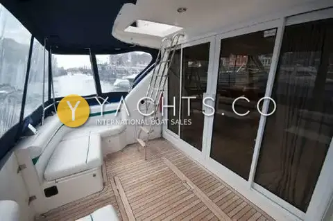 Fairline Phantom 41: aft cockpit with teak deck, corner seating, flybridge ladder and glass doors to the saloon