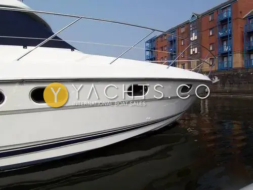 Fairline Phantom 41 Reduced: starboard bow close-up showing white hull, oval portholes and guard rails beside brick flats