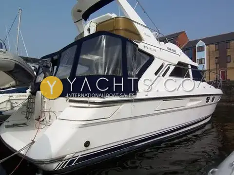 Fairline Phantom 41 Reduced: stern quarter view with navy cockpit canopy, bathing platform and flybridge in marina