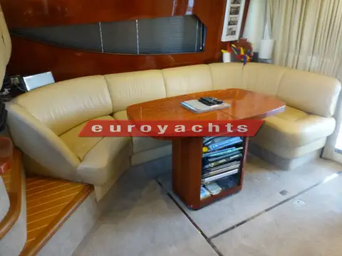 Fairline Phantom 46: curved cream leather settee around a high-gloss wooden dining table in the saloon