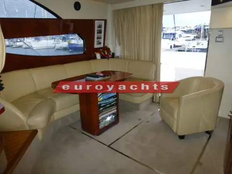 Fairline Phantom 46: saloon settee, dining table and cream leather tub chair beside the cockpit door