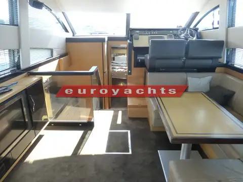 Fairline Squadron 42: saloon looking forward past dining table and helm seat to glass galley partition