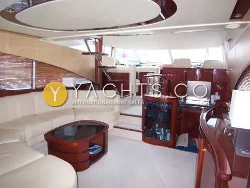 Fairline Squadron 58: saloon with curved cream leather sofa, cherry coffee table, drinks cabinet and steps up to the lower helm