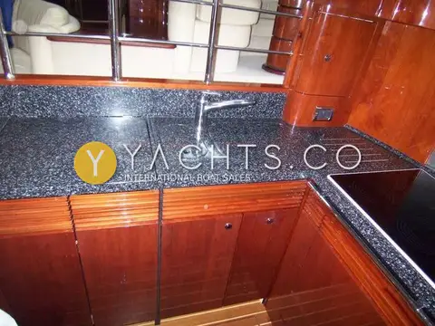 Fairline Squadron 58: galley with dark speckled worktop, sink with mixer tap and cherry cupboards below