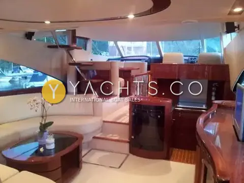 Fairline Squadron 58: saloon with cream curved settee, cherry joinery and steps up to the raised dinette and helm