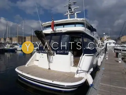 Fairline Squadron 58: stern view in a marina showing teak bathing platform, passerelle and navy cockpit canopy