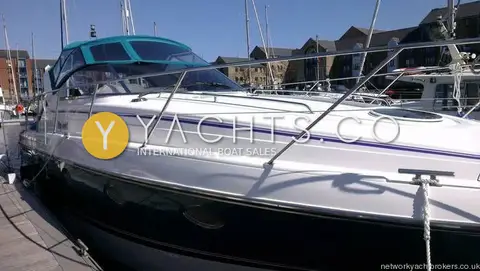 Fairline Targa 38: port bow quarter alongside a pontoon, purple stripe on white topsides and stainless guardrails