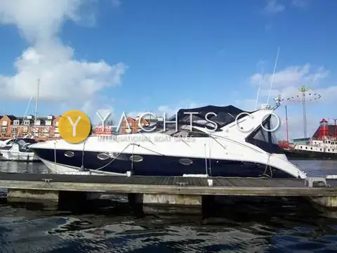 Fairline Targa 40: port side profile with dark blue hull and canopy up, alongside a pontoon