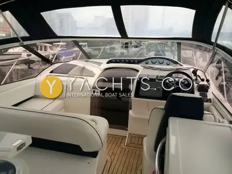 Fairline Targa 40: cockpit under canopy showing cream seating, teak sole and helm to starboard