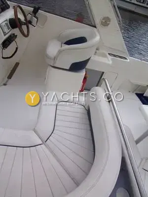Falcon 27: cockpit seating with white and navy cushions leading to the helm seat and wooden wheel
