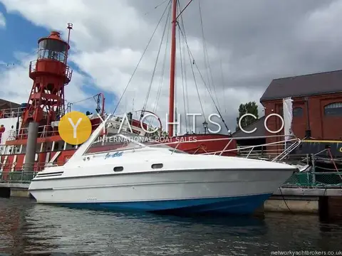 Falcon 27: starboard side view alongside a red lightship and brick warehouse under cloudy sky