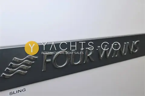 Four Winns Vista 255: close-up of the chrome Four Winns logo on the dark grey hull band