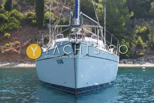 Franchini 45L: bow view at anchor in a wooded cove, anchor chain down and furled genoa visible
