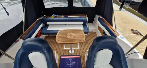 Galeon Galia 700 Walk-around Sport Fisher: cockpit from the helm seats, teak table, blue upholstered bench and teak-effect decking