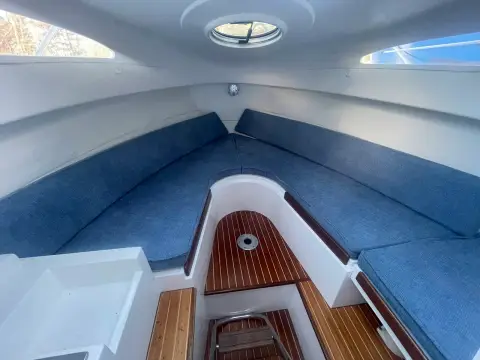 Galeon Galia 700 Walk-around Sport Fisher: forward cabin V-shaped seating in blue fabric beneath an opening overhead hatch