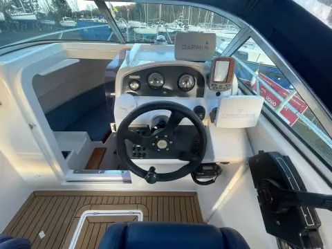 Galeon Galia 700 Walk-around Sport Fisher: helm with black wheel, gauges, fishfinder and throttle beside the windscreen