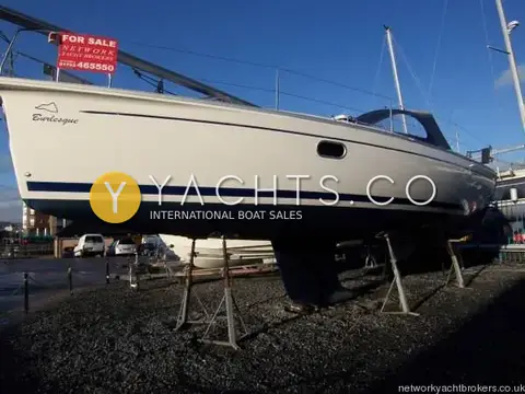 Gib Sea 37: port bow view ashore on stands with blue boot stripe and marina flats behind