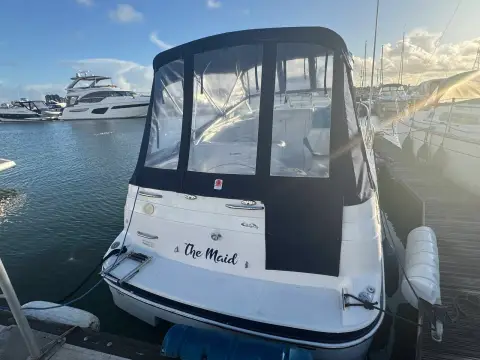 Glastron GT 249: transom and full camper cover afloat in a marina at sunset