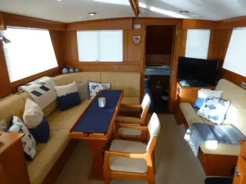 Grand Banks 42: saloon looking aft over dining table and settee towards television and steps